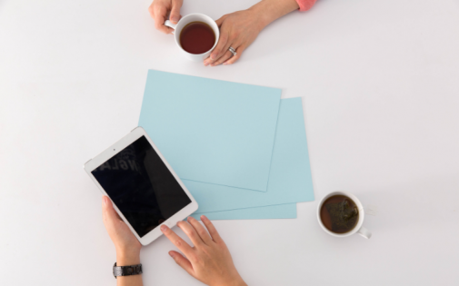 Two people with tea use an iPad to evaluate different MBA Programs