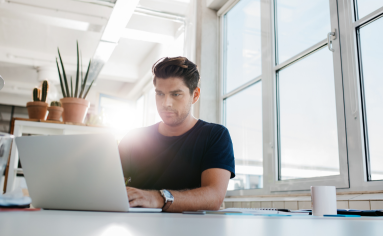 A man on their laptop preparing for the 2022 Kellogg EMBA Essay