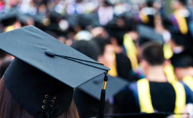 Graduation cap with graduating students in the background